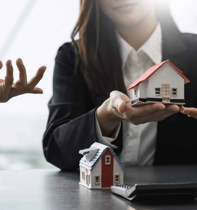 Conseiller protégeant symboliquement un modèle de maison à Caen pour diagnostic immobilier.
