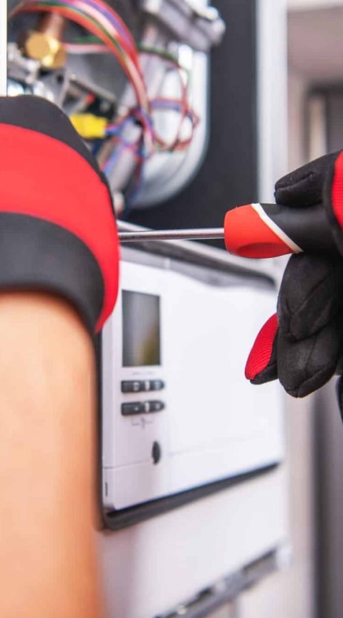 Technicien avec des gants utilisant un tournevis sur un équipement gaz à Caen pour diagnostic gaz.